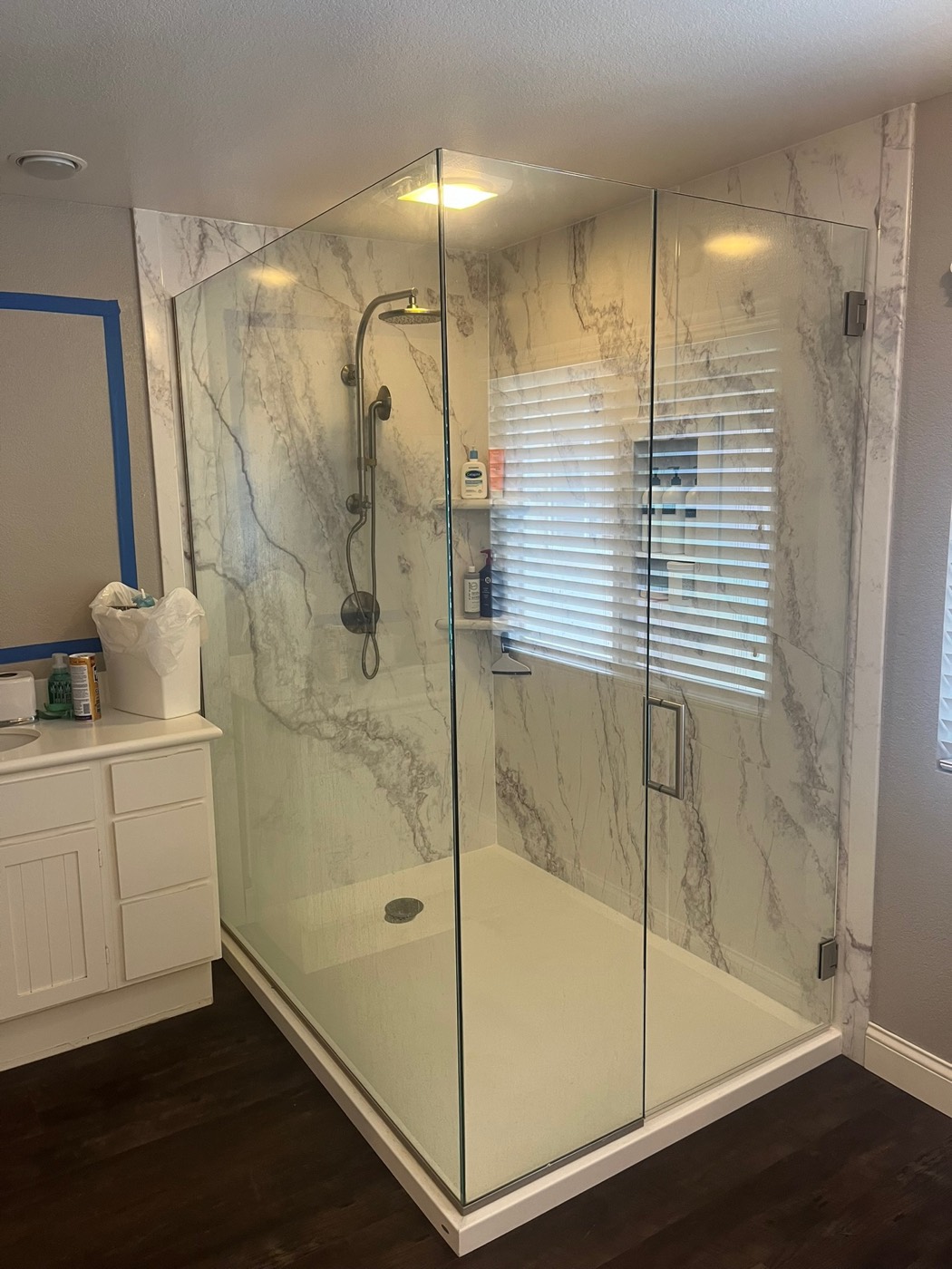 Walk-in shower with dramatic Calacatta marble-look stone panels and a frameless glass enclosure