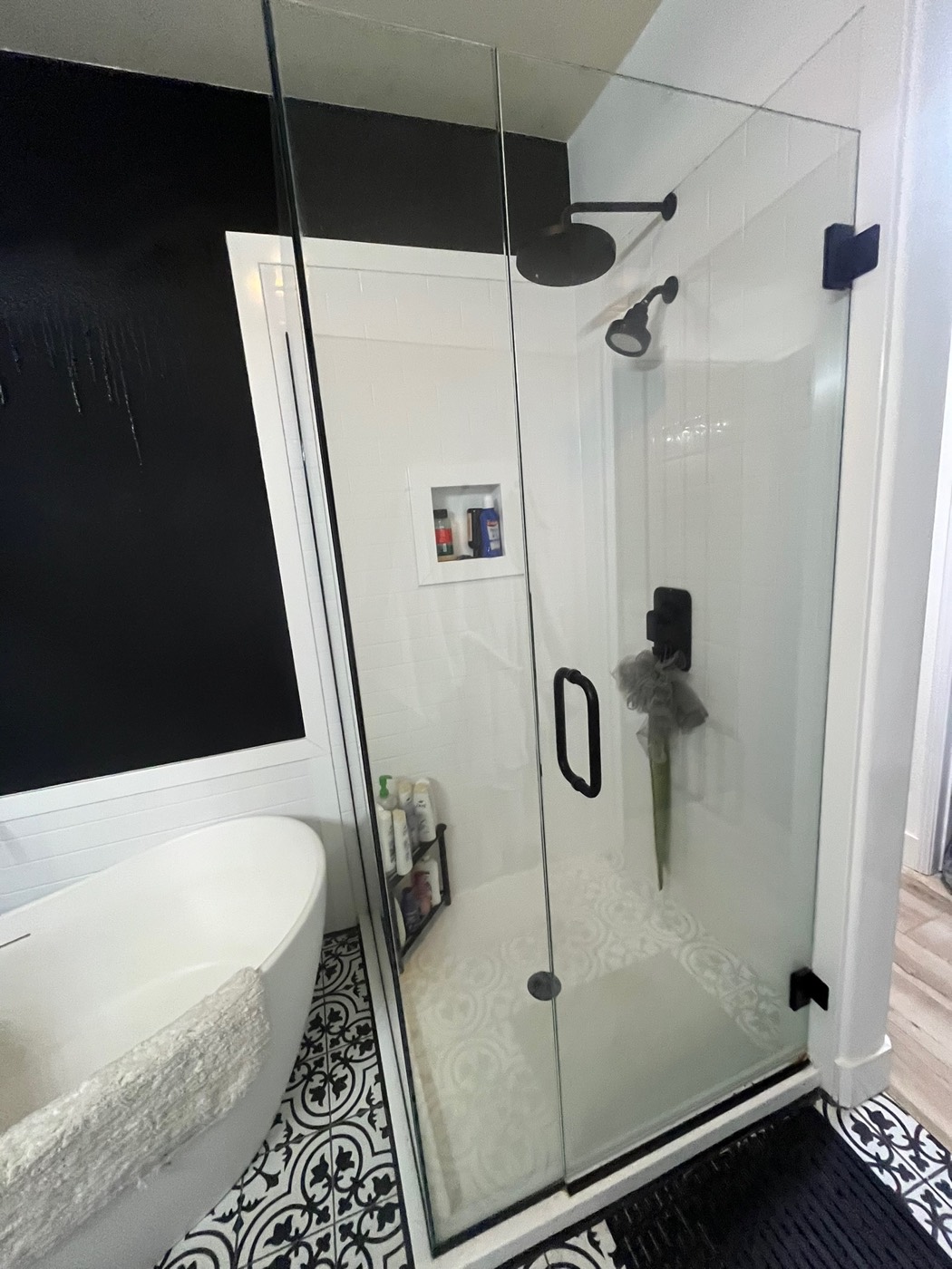Modern white subway-look shower with a frameless glass enclosure and black fixtures