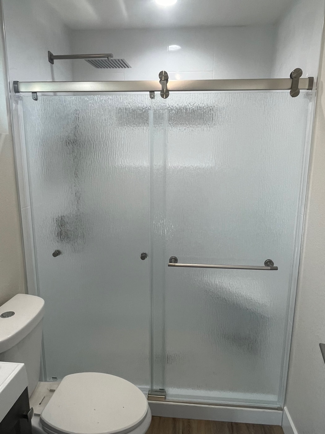 Grout-free shower with a brushed-nickel sliding glass door